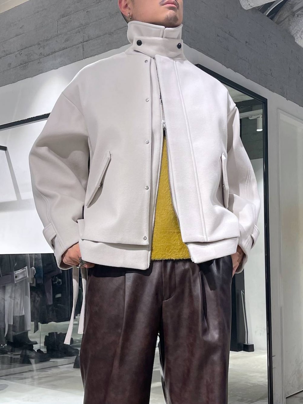 ブラック系のトートバッグ、ホワイト系のブルゾン、イエロー系のニット/セーターを着用したメンズの秋コーディネートの6枚目の写真
