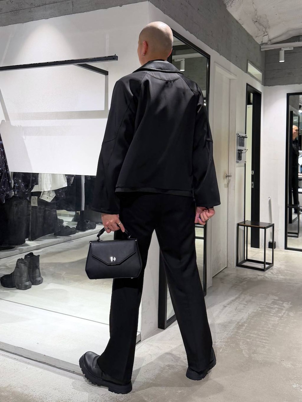 ブラック系のスラックス、ブラック系のハンドバッグ、ブラック系のドレスシューズを着用したメンズの春コーディネートの3枚目の写真