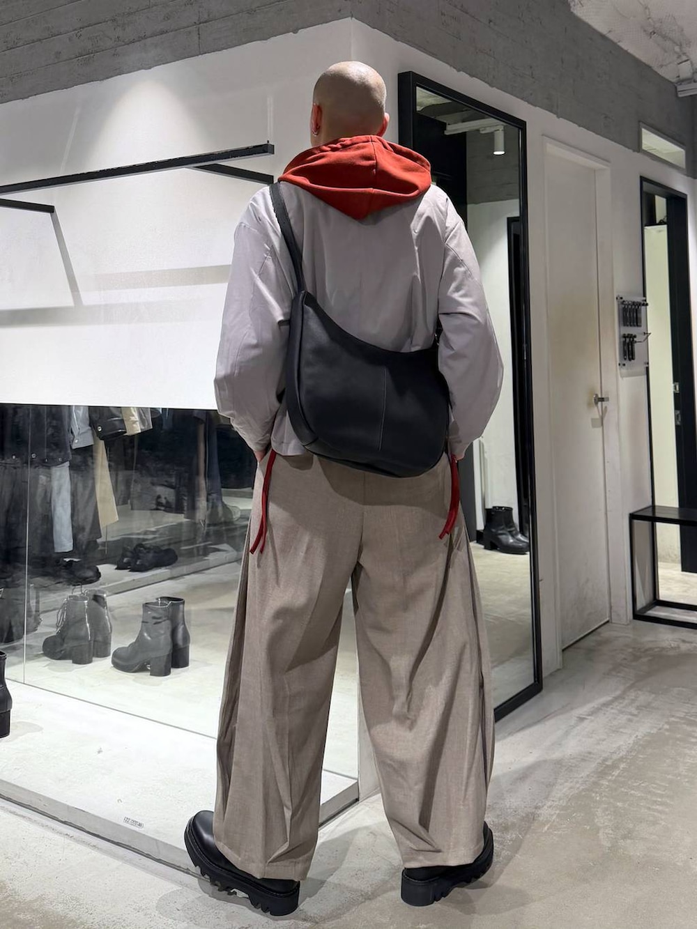 オレンジ系のパーカー、ブラック系のドレスシューズ、ブラック系のショルダーバッグを着用したメンズの春コーディネートの3枚目の写真