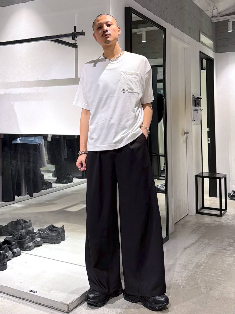 ブラック系のスニーカー、ホワイト系のTシャツ/カットソー、ブラック系のスラックスを着用したメンズの夏コーディネートの5枚目の写真