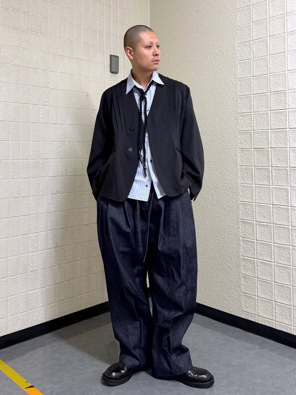 ブラック系のノーカラージャケット、ブルー系のデニムパンツを着用したメンズの春コーディネートの2枚目の写真