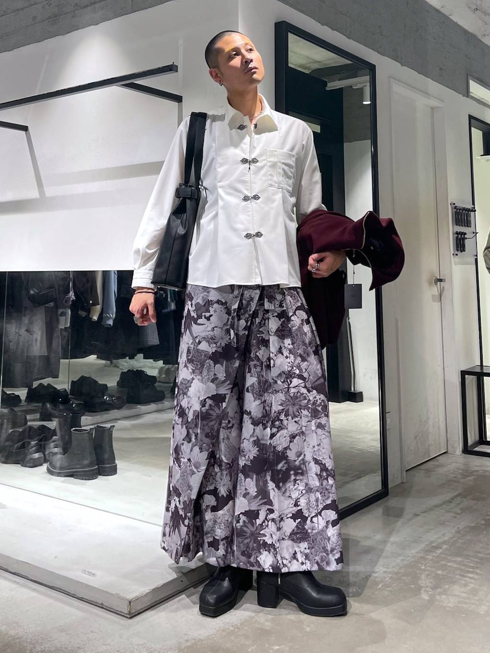 レッド系のブルゾン、ブラック系のトートバッグ、ブラック系のブーツを着用したメンズの秋コーディネートの5枚目の写真