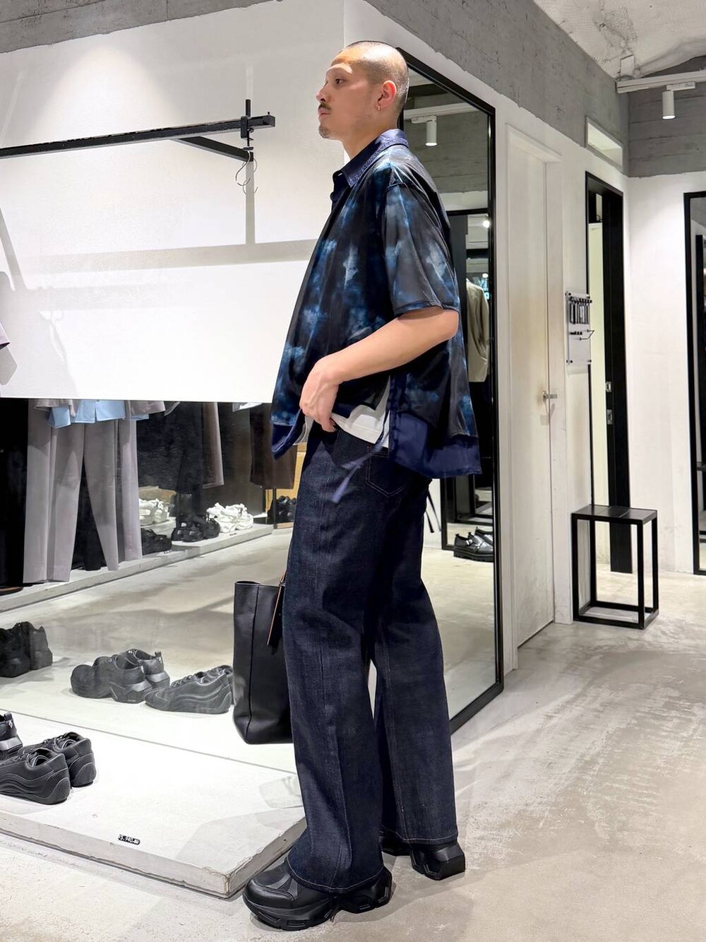 ブラック系のスニーカー、ホワイト系のTシャツ/カットソー、ブラック系のトートバッグを着用したメンズの夏コーディネートの2枚目の写真