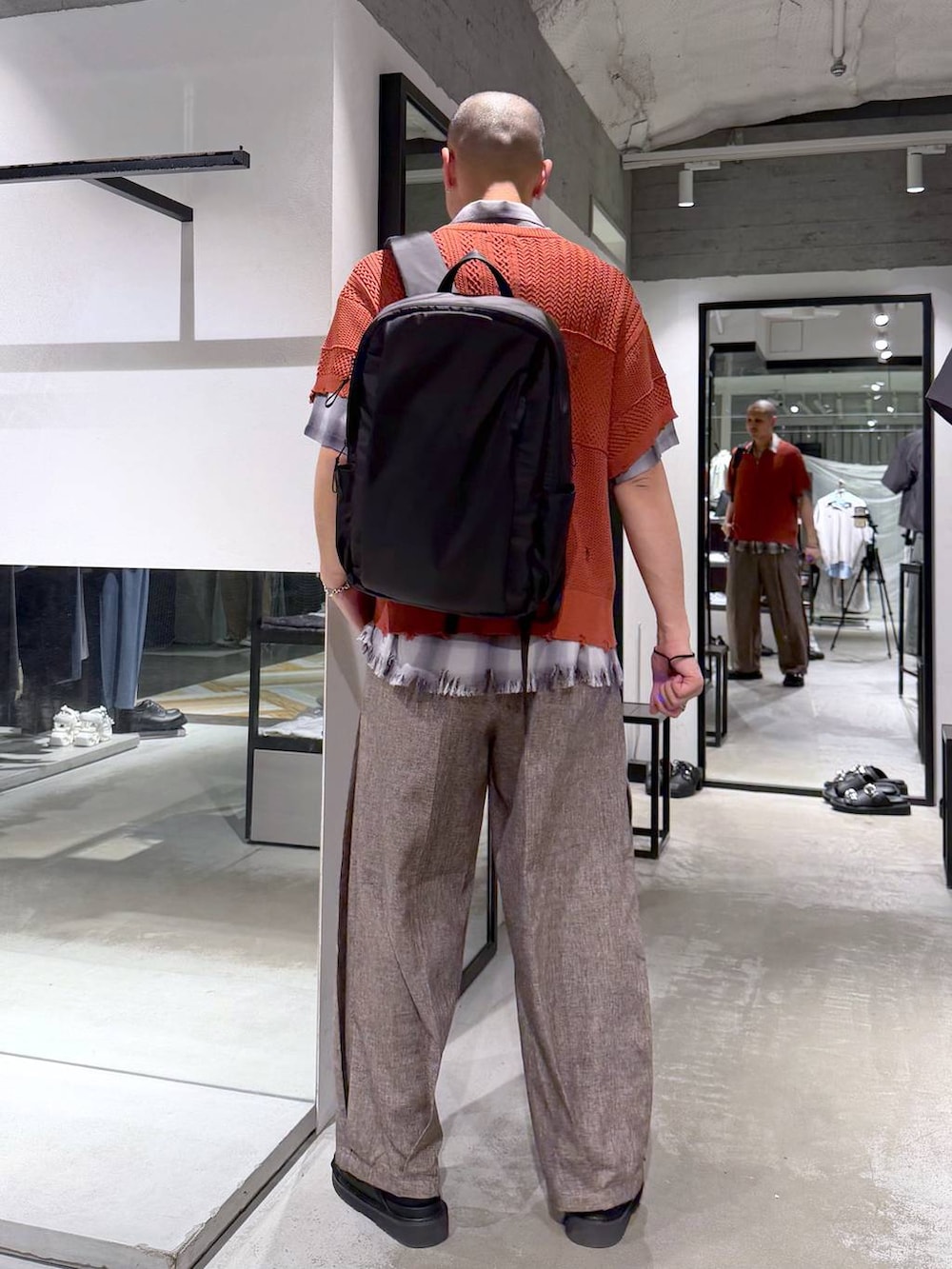 ブラック系のバックパック/リュック、ブラック系のサンダル、ブラウン系のスラックスを着用したメンズの春コーディネートの3枚目の写真
