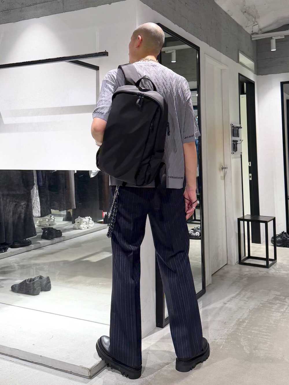 ブルー系のスラックス、ブラック系のドレスシューズ、ブラック系のバックパック/リュックを着用したメンズの夏コーディネートの3枚目の写真