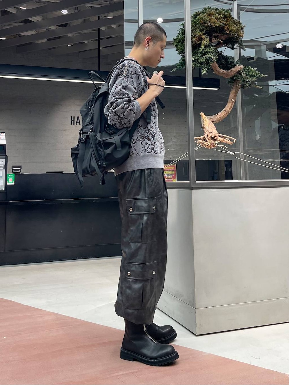 グレー系のニット/セーター、グレー系のカーゴパンツ、ブラック系のバックパック/リュックを着用したメンズの秋コーディネートの4枚目の写真