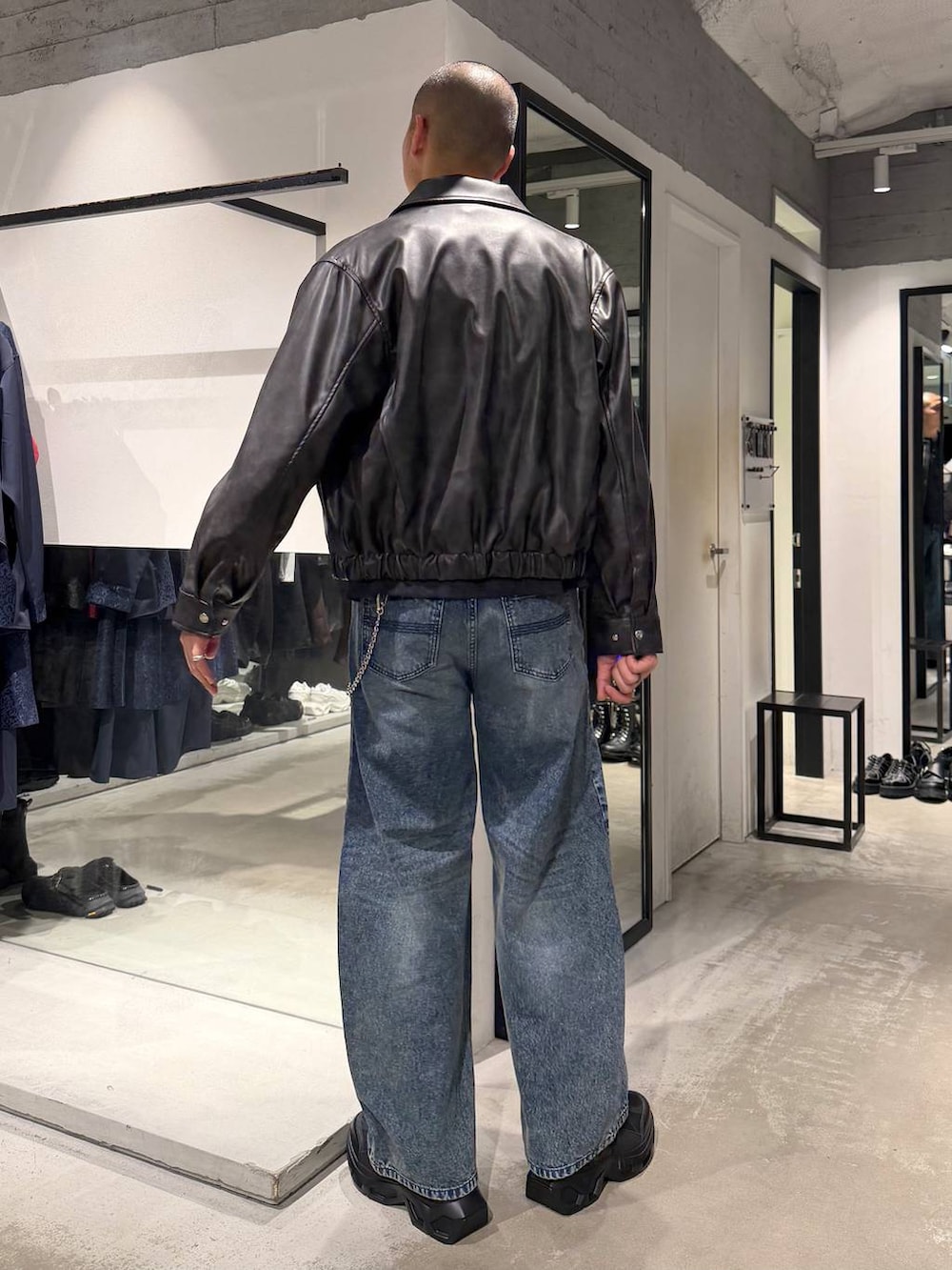 ブルー系のデニムパンツ、ブラック系のTシャツ/カットソー、ブラック系のスニーカーを着用したメンズの秋コーディネートの3枚目の写真