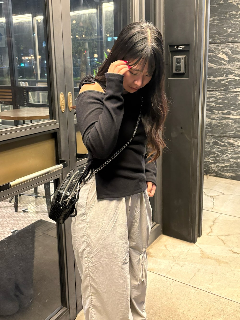 グレー系のその他パンツ、ブラック系のニット/セーター、ブラック系のショルダーバッグを着用したレディースの秋コーディネートの2枚目の写真