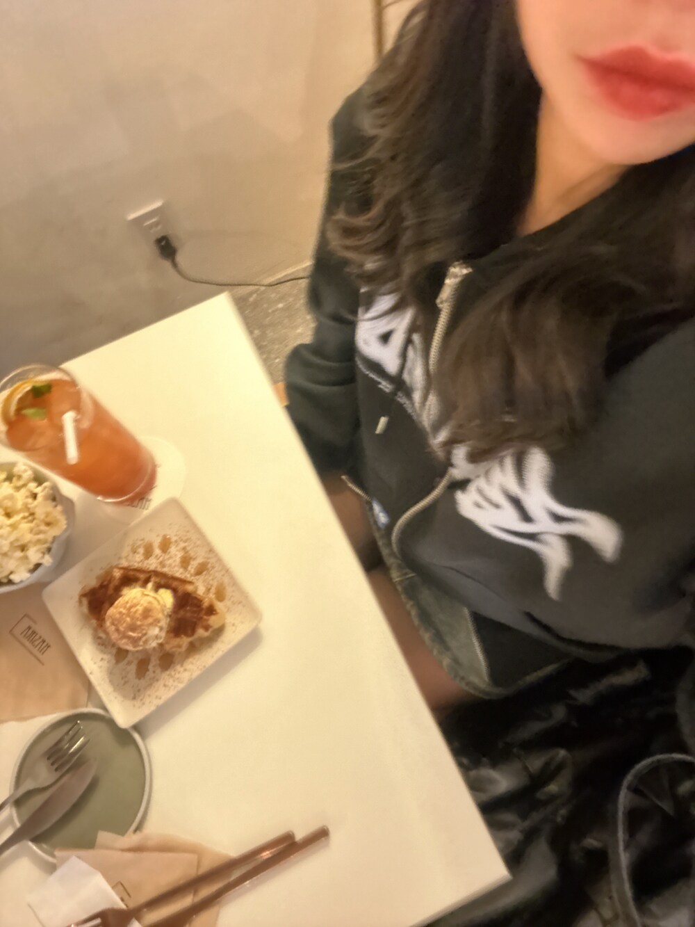 ブラック系のパーカー、ブラック系のダウンジャケット/コート、ホワイト系のスニーカーを着用したレディースの春コーディネートの2枚目の写真