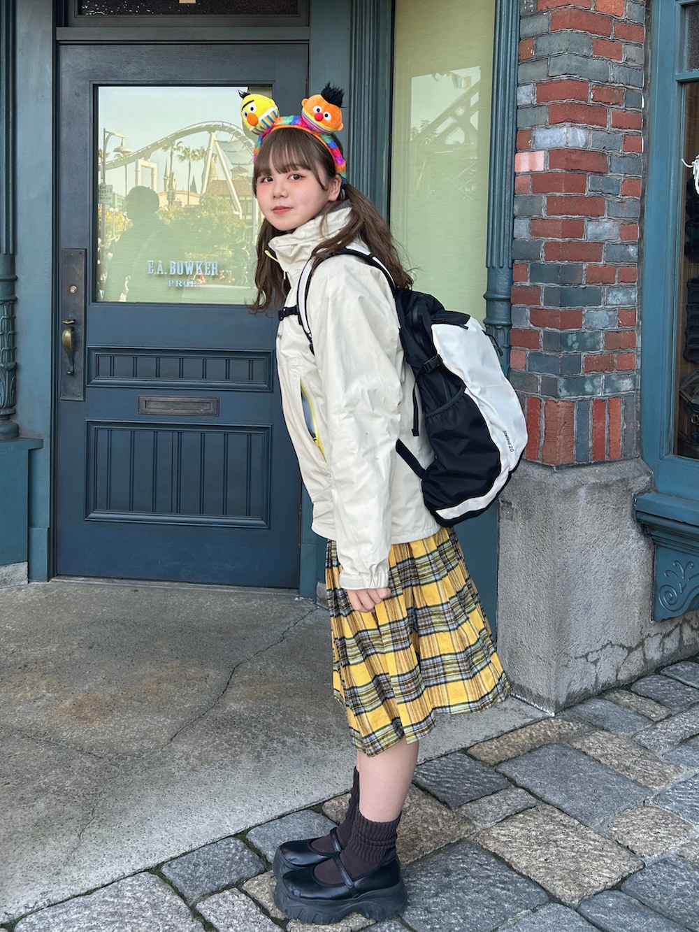 ベージュ系のナイロンジャケット、イエロー系のスカート、ブラック系のスニーカーを着用したレディースの冬コーディネートの2枚目の写真