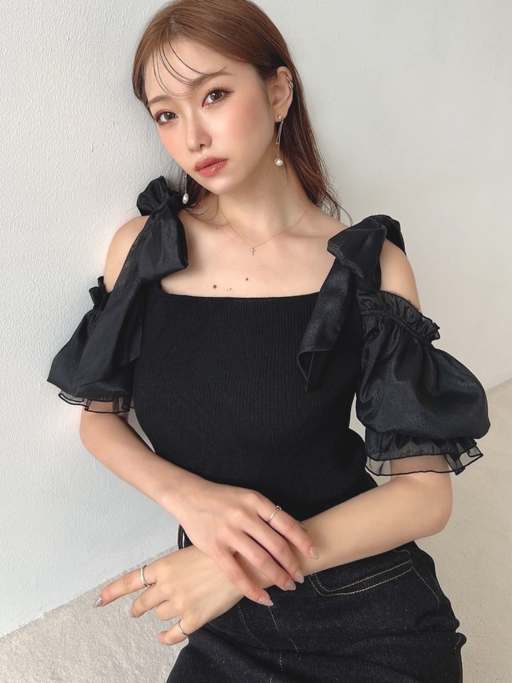 ブラック系のニット/セーター、ブラック系のスカート、ピンク系のハンドバッグを着用したレディースの夏コーディネートの3枚目の写真