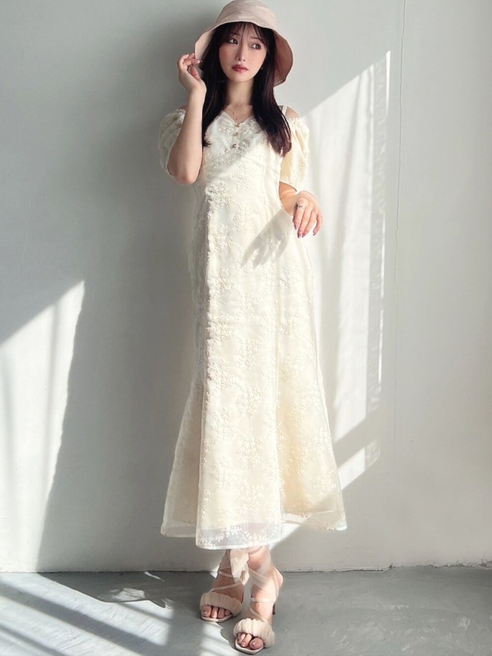 ホワイト系のワンピース、ベージュ系のサンダル、ピンク系のハットを着用したレディースの春コーディネートの3枚目の写真