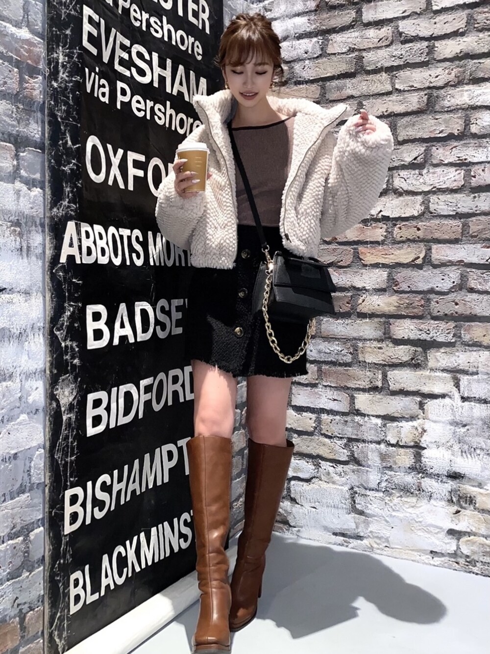 ホワイト系のブルゾン、ブラウン系のブーツ、ブラック系のその他パンツを着用したレディースの冬コーディネートの2枚目の写真