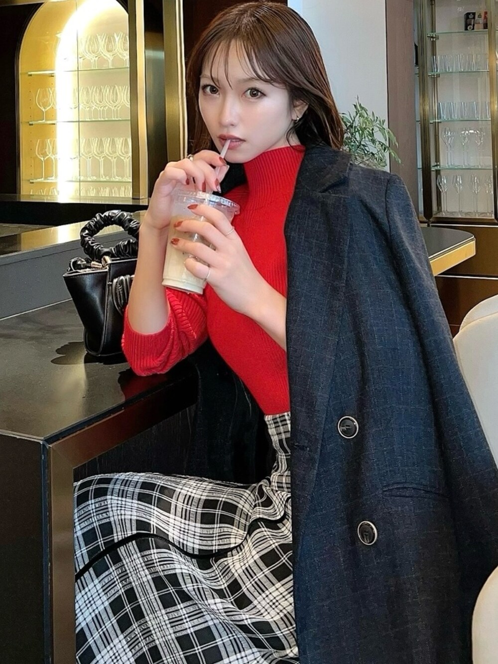 ブラック系のスカート、レッド系のニット/セーター、グレー系のテーラードジャケットを着用したレディースの秋コーディネートの2枚目の写真