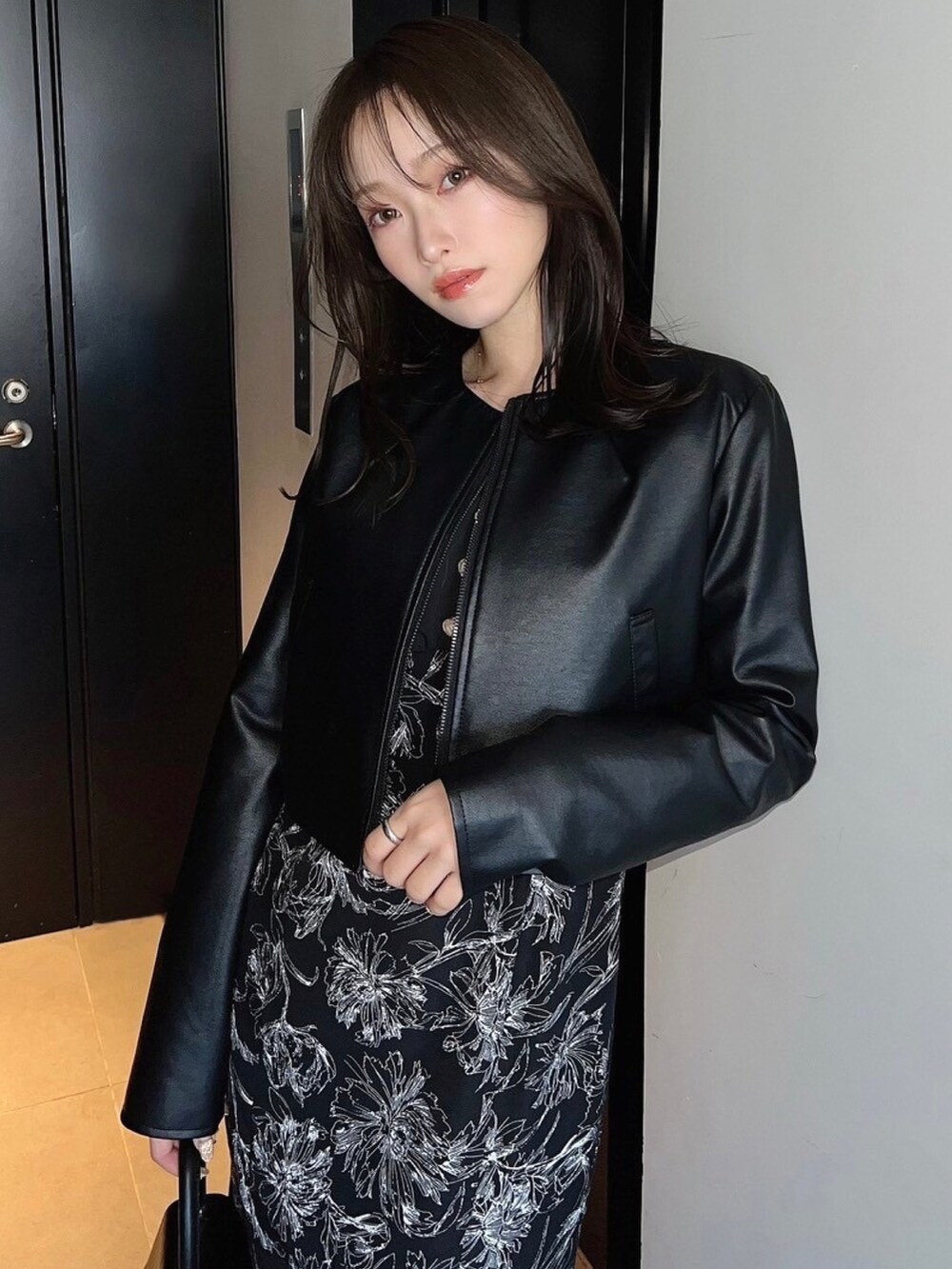 ブラック系のハンドバッグ、ブラック系のライダースジャケット、ブラック系のワンピースを着用したレディースの春コーディネートの2枚目の写真