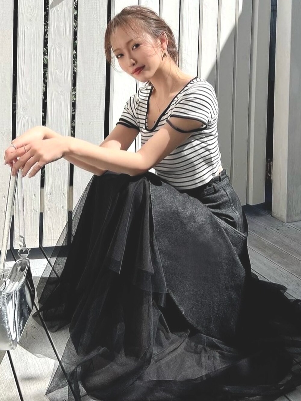 ブラック系のデニムスカート、その他のTシャツ/カットソー、ホワイト系のサンダルを着用したレディースの春コーディネートの2枚目の写真