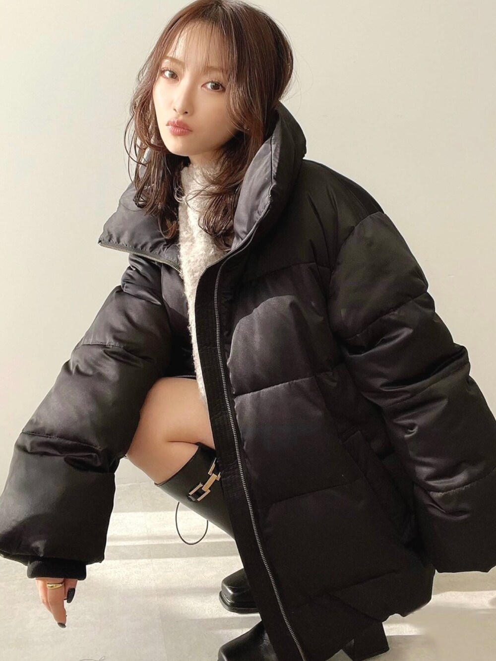 ブラック系のダウンジャケット/コート、ブラック系のブーツ、ベージュ系のニット/セーターを着用したレディースの冬コーディネートの3枚目の写真