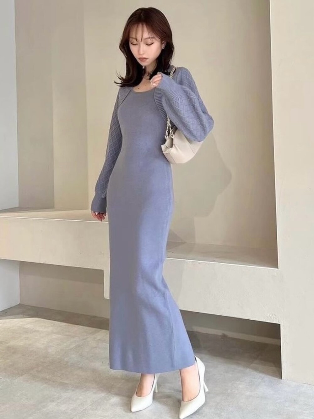 ブルー系のワンピース、ホワイト系のパンプス、ベージュ系のハンドバッグを着用したレディースの冬コーディネートの2枚目の写真