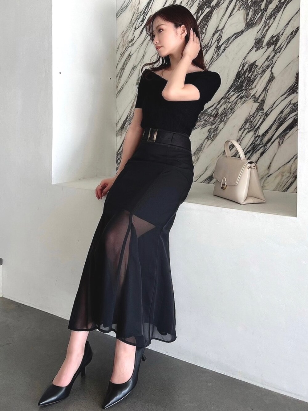 ブラック系のスカートを着用したレディースの春コーディネートの2枚目の写真