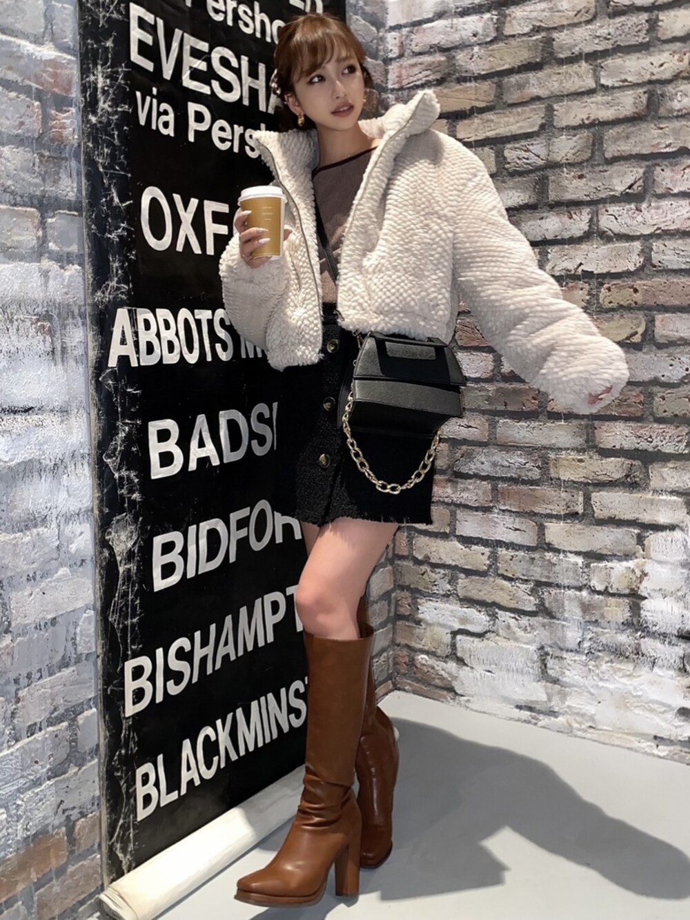 ホワイト系のブルゾン、ブラウン系のブーツ、ブラック系のその他パンツを着用したレディースの冬コーディネートの3枚目の写真