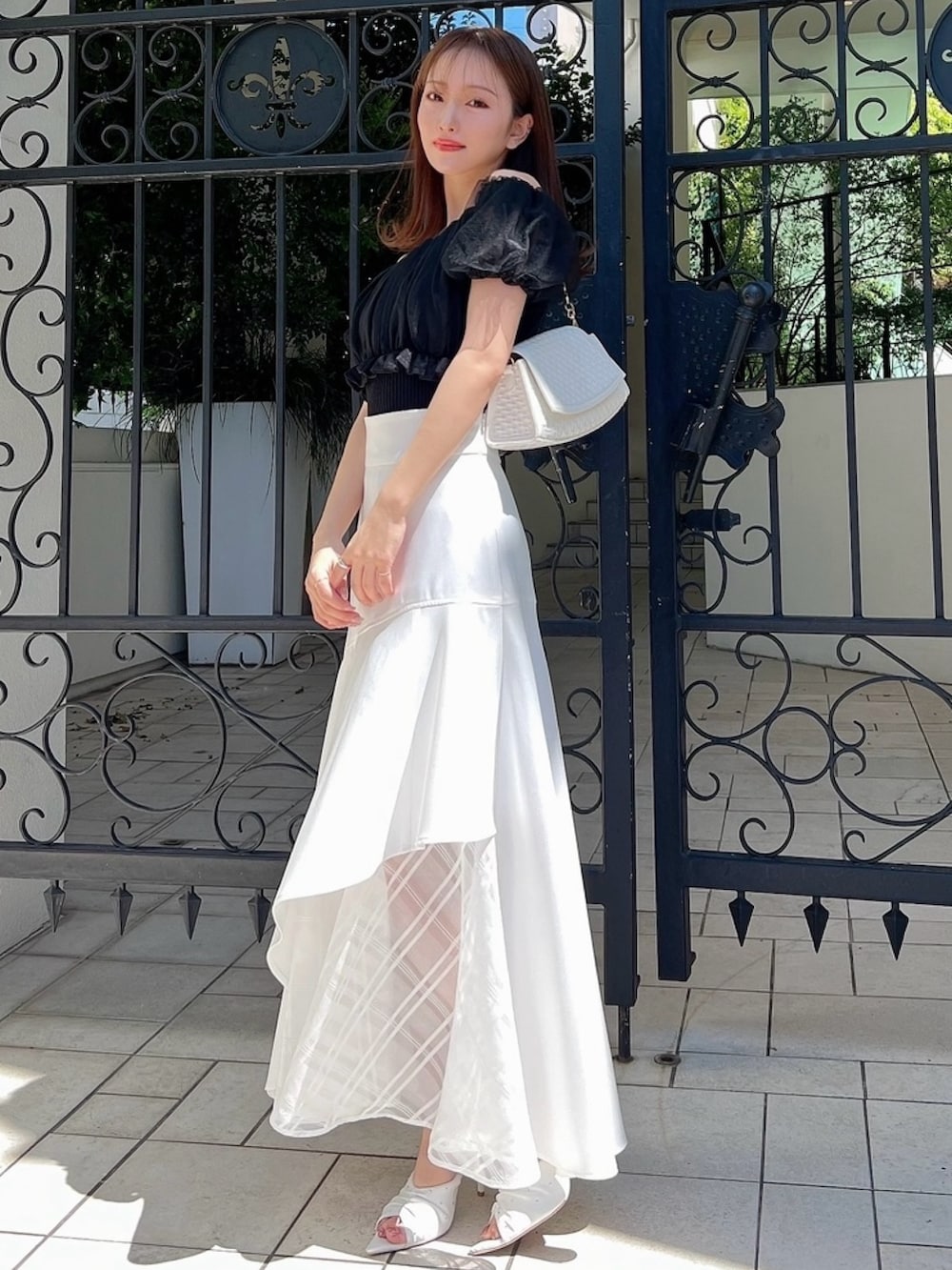 ホワイト系のスカート、ブラック系のシャツ/ブラウス、ホワイト系のハンドバッグを着用したレディースの春コーディネートの4枚目の写真