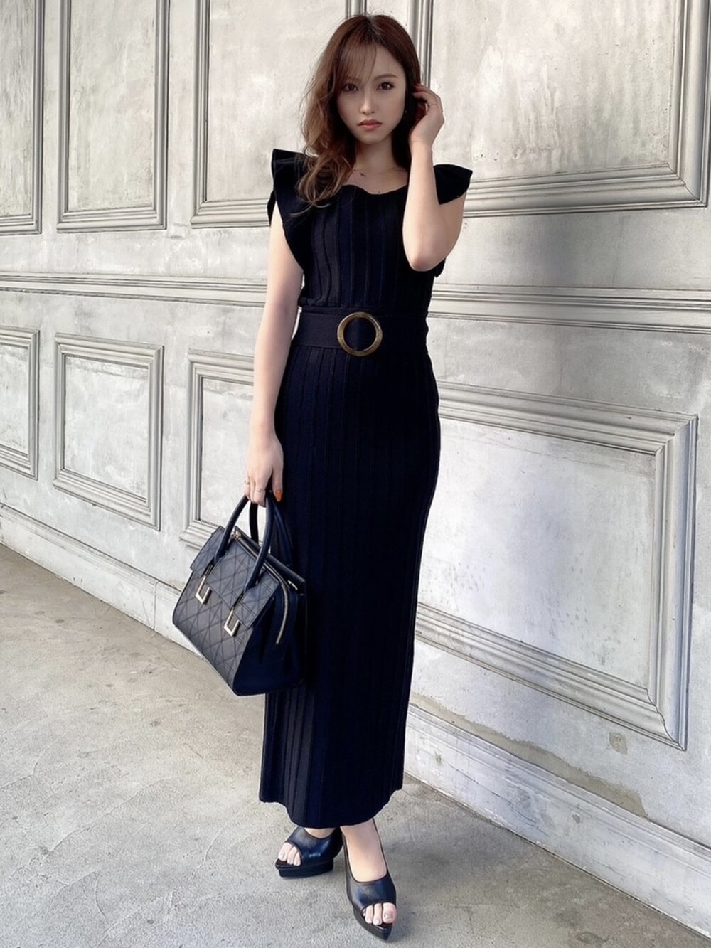 ブラック系のパンプス、ブラック系のワンピース、ブラック系のハンドバッグを着用したレディースの春コーディネートの3枚目の写真