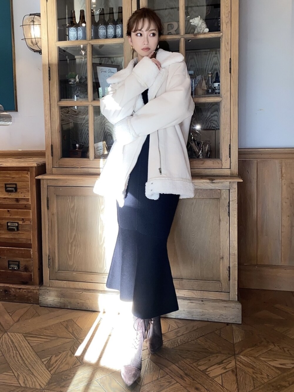 ブラック系のスカート、ブラック系のニット/セーター、ホワイト系のムートンコートを着用したレディースの冬コーディネートの3枚目の写真