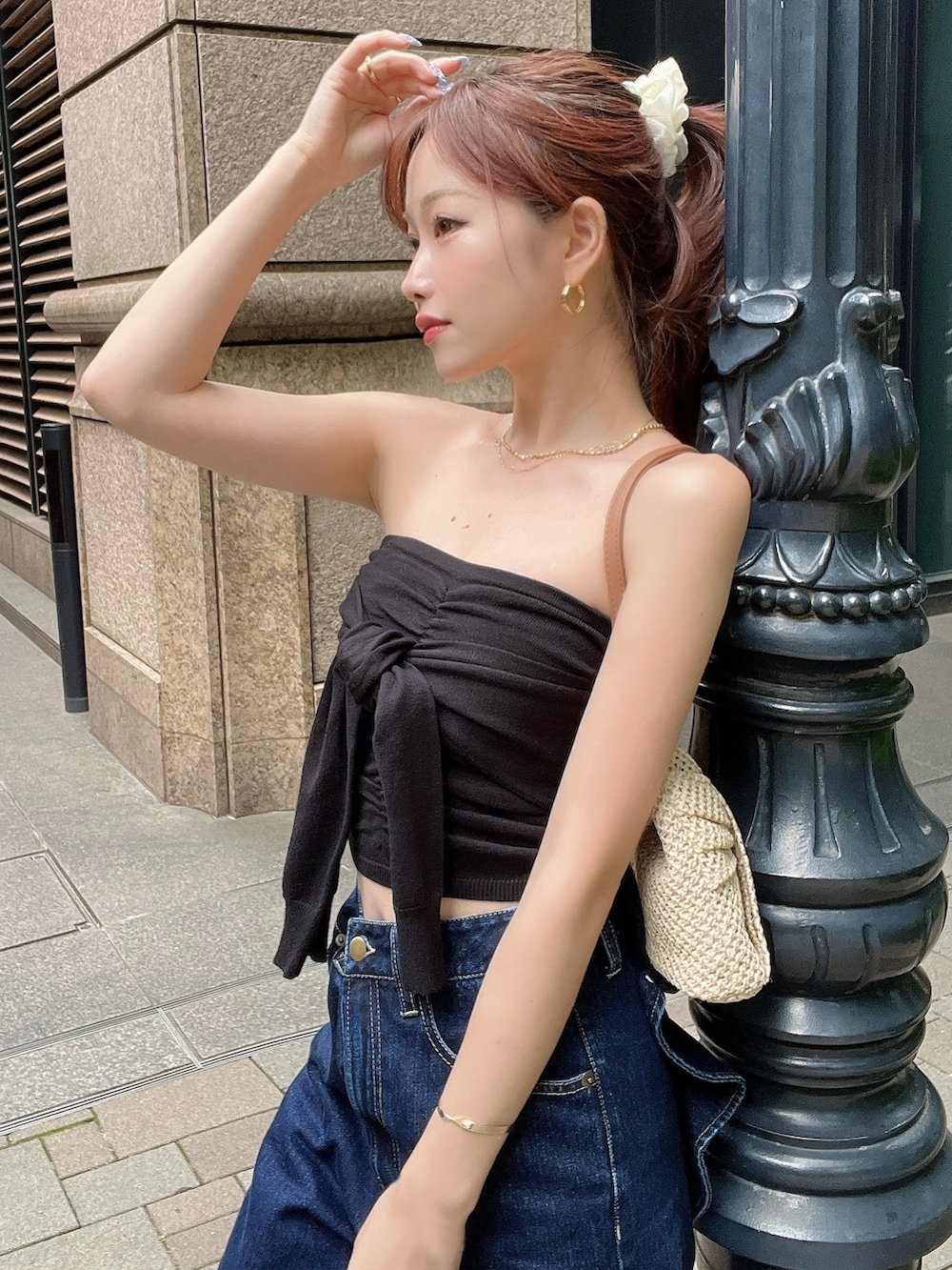 ブラック系のキャミソール、ブルー系のデニムパンツ、ベージュ系のハンドバッグを着用したレディースの夏コーディネートの3枚目の写真