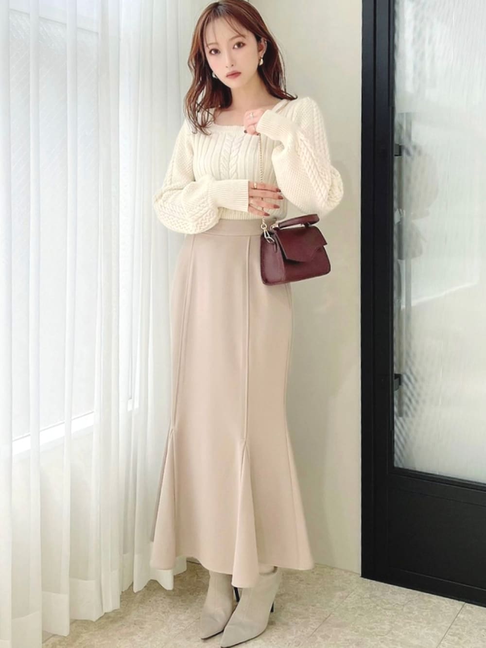ホワイト系のニット/セーター、ベージュ系のスカート、ホワイト系のブーツを着用したレディースの秋コーディネートの2枚目の写真