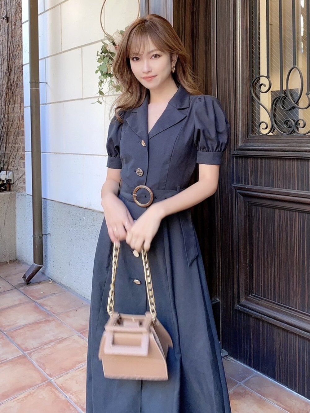 ブラック系のワンピース、ブラック系のパンプス、ブラウン系のショルダーバッグを着用したレディースの冬コーディネートの4枚目の写真