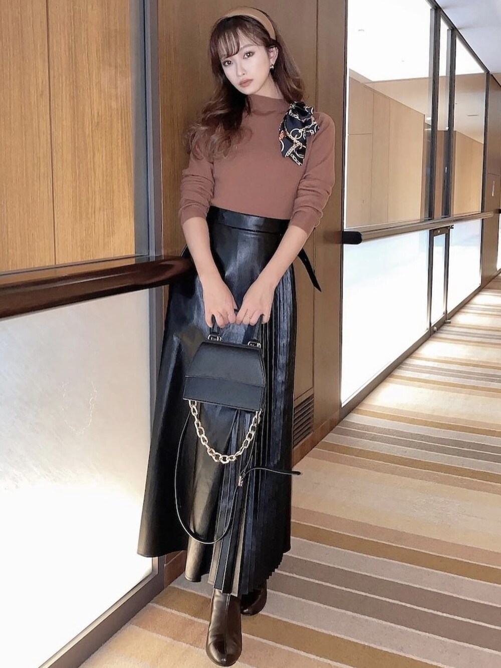 ブラック系のスカート、ブラウン系のブーツ、ブラウン系のニット/セーターを着用したレディースの秋コーディネートの2枚目の写真