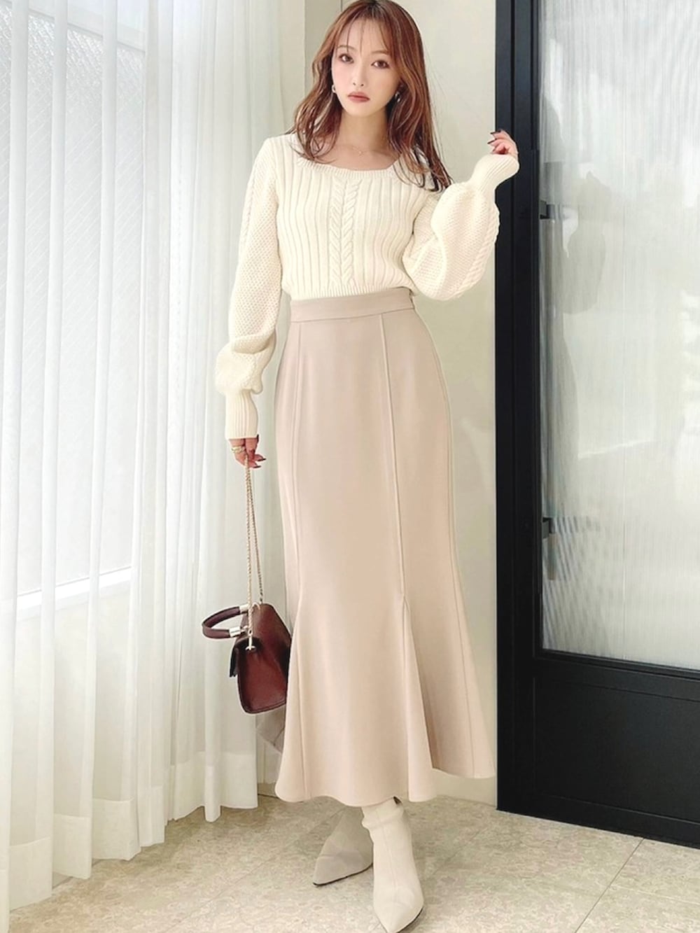 ホワイト系のニット/セーター、ベージュ系のスカート、ホワイト系のブーツを着用したレディースの秋コーディネートの3枚目の写真