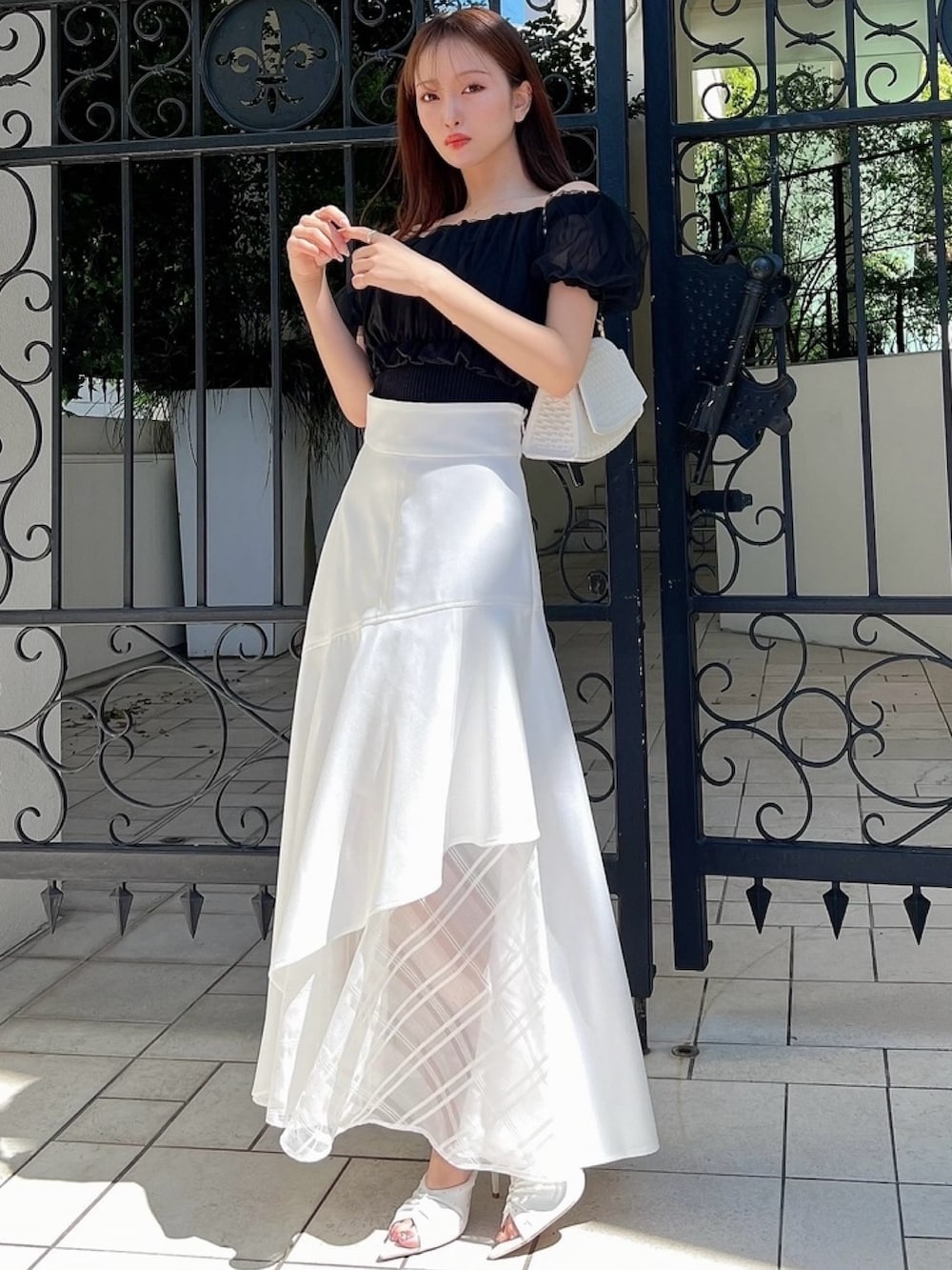 ホワイト系のスカート、ブラック系のシャツ/ブラウス、ホワイト系のハンドバッグを着用したレディースの春コーディネートの3枚目の写真