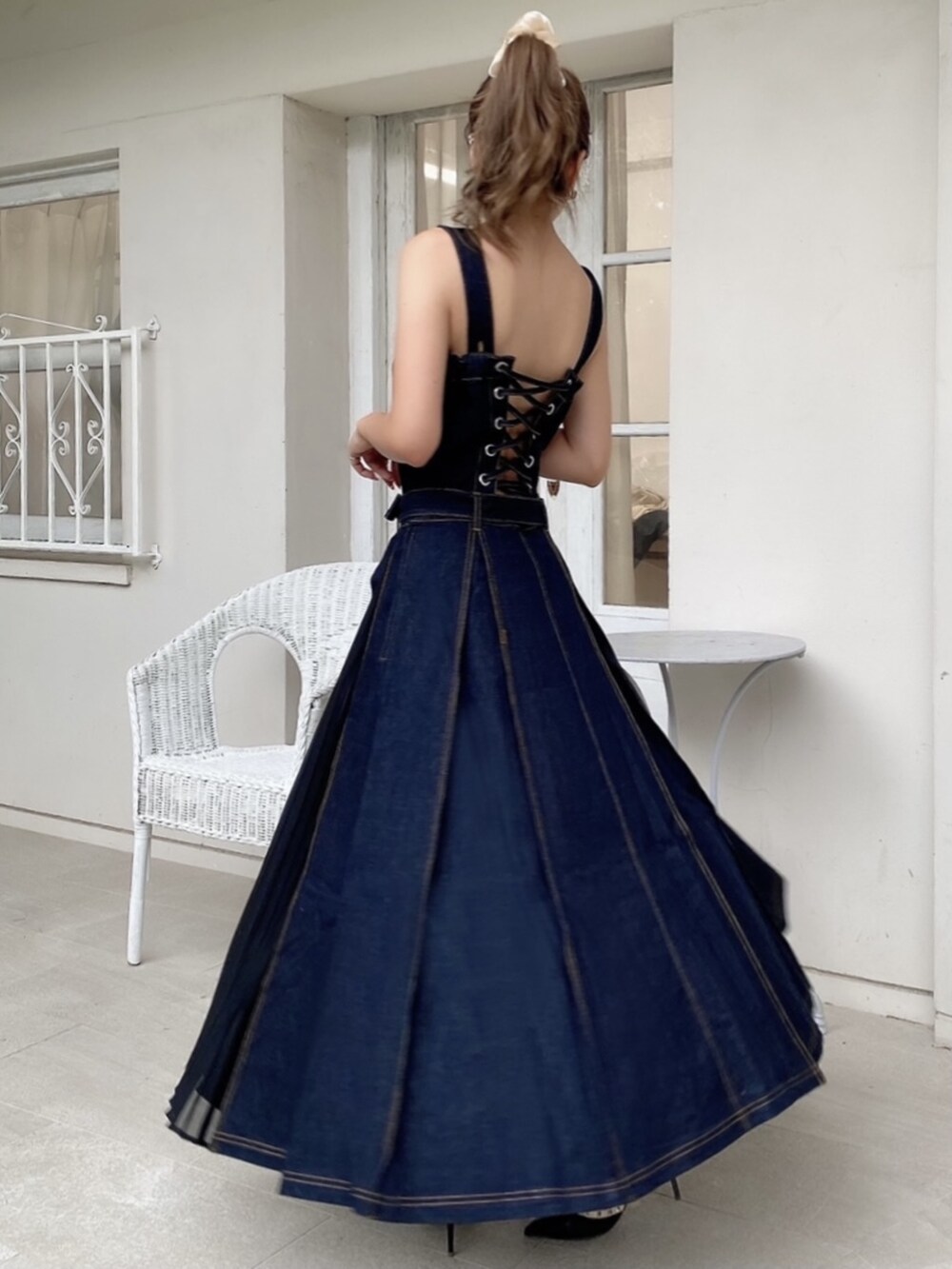 ブラック系のパンプス、ブルー系のジャンパースカート、ピンク系のシュシュを着用したレディースの夏コーディネートの2枚目の写真