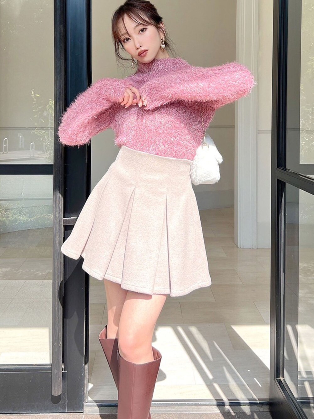 ピンク系のニット/セーター、ホワイト系のハンドバッグを着用したレディースの冬コーディネートの3枚目の写真