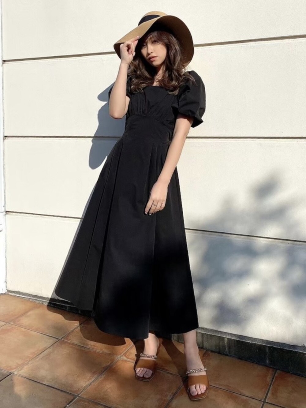 ブラック系のワンピース、ブラウン系のサンダル、ブラック系のハットを着用したレディースの春コーディネートの2枚目の写真