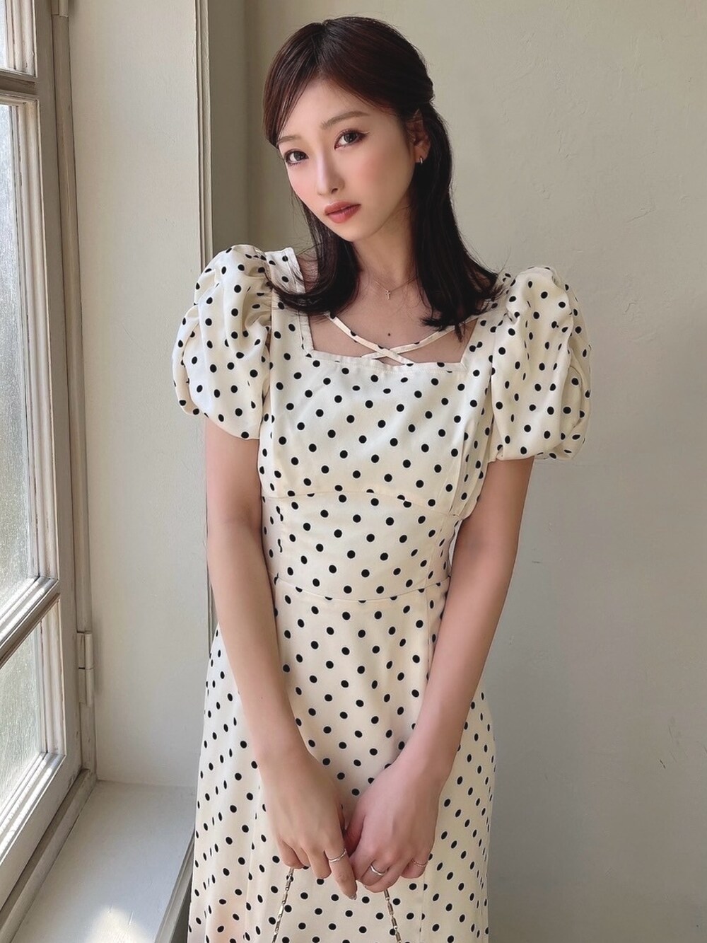 ホワイト系のワンピース、ホワイト系のサンダル、ピンク系のハンドバッグを着用したレディースの春コーディネートの2枚目の写真