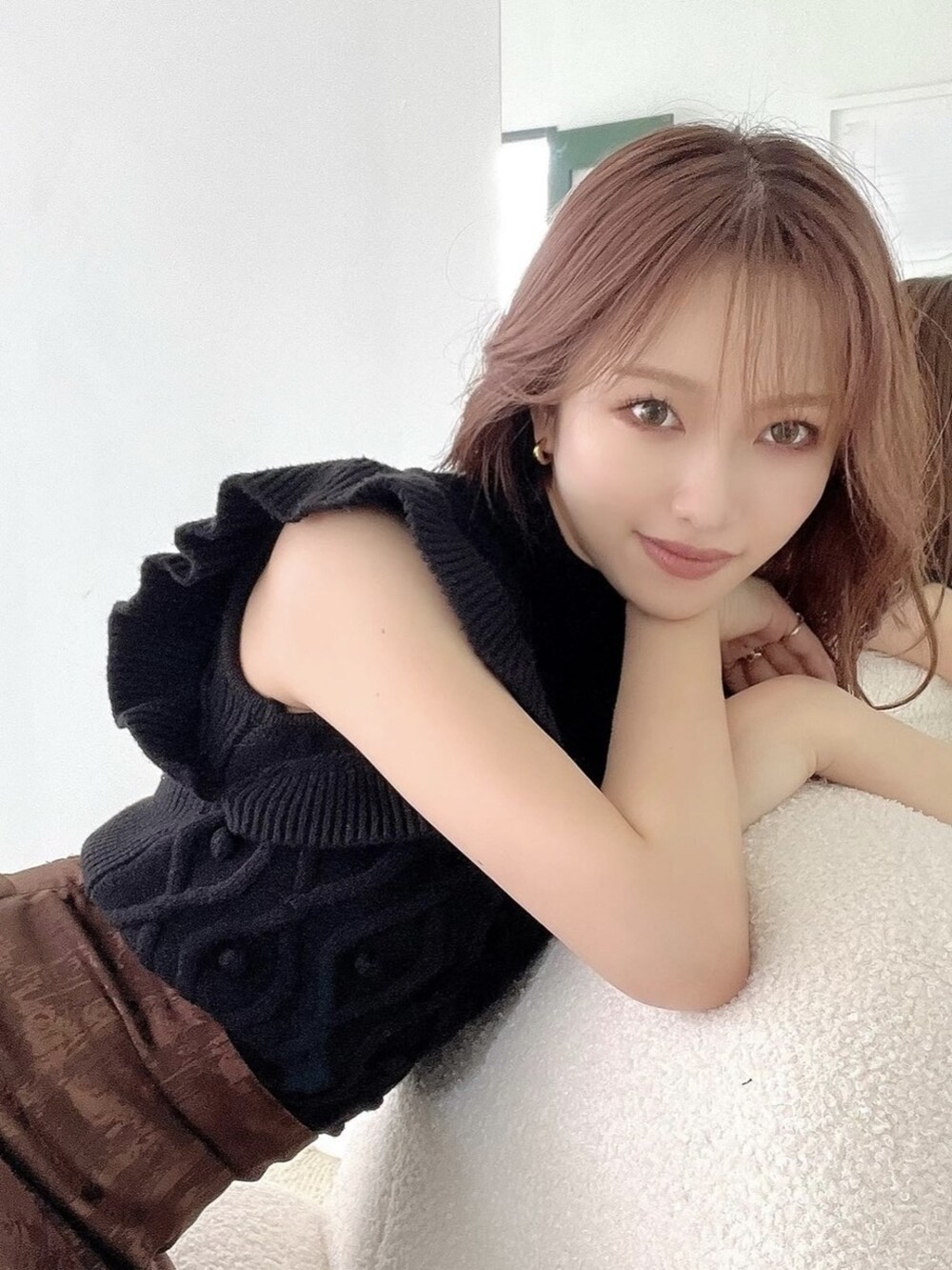 ブラック系のニット/セーター、ブラウン系のスカート、ブラック系のパンプスを着用したレディースの夏コーディネートの2枚目の写真