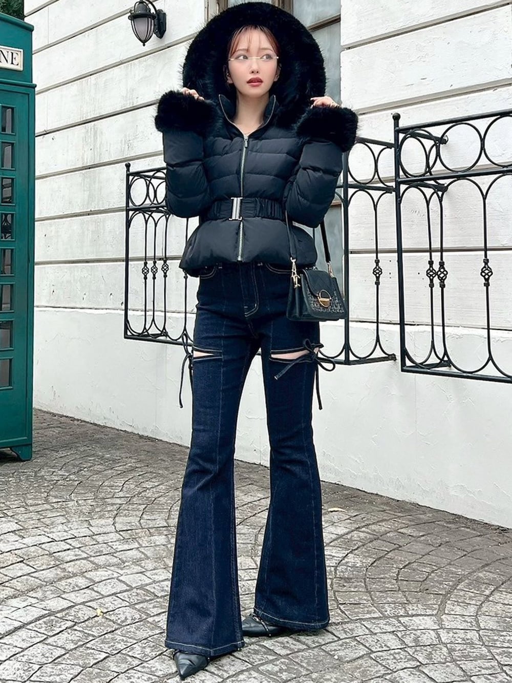 ブラック系のダウンジャケット/コート、ブルー系のデニムパンツ、ブラック系のハンドバッグを着用したレディースの秋コーディネートの4枚目の写真