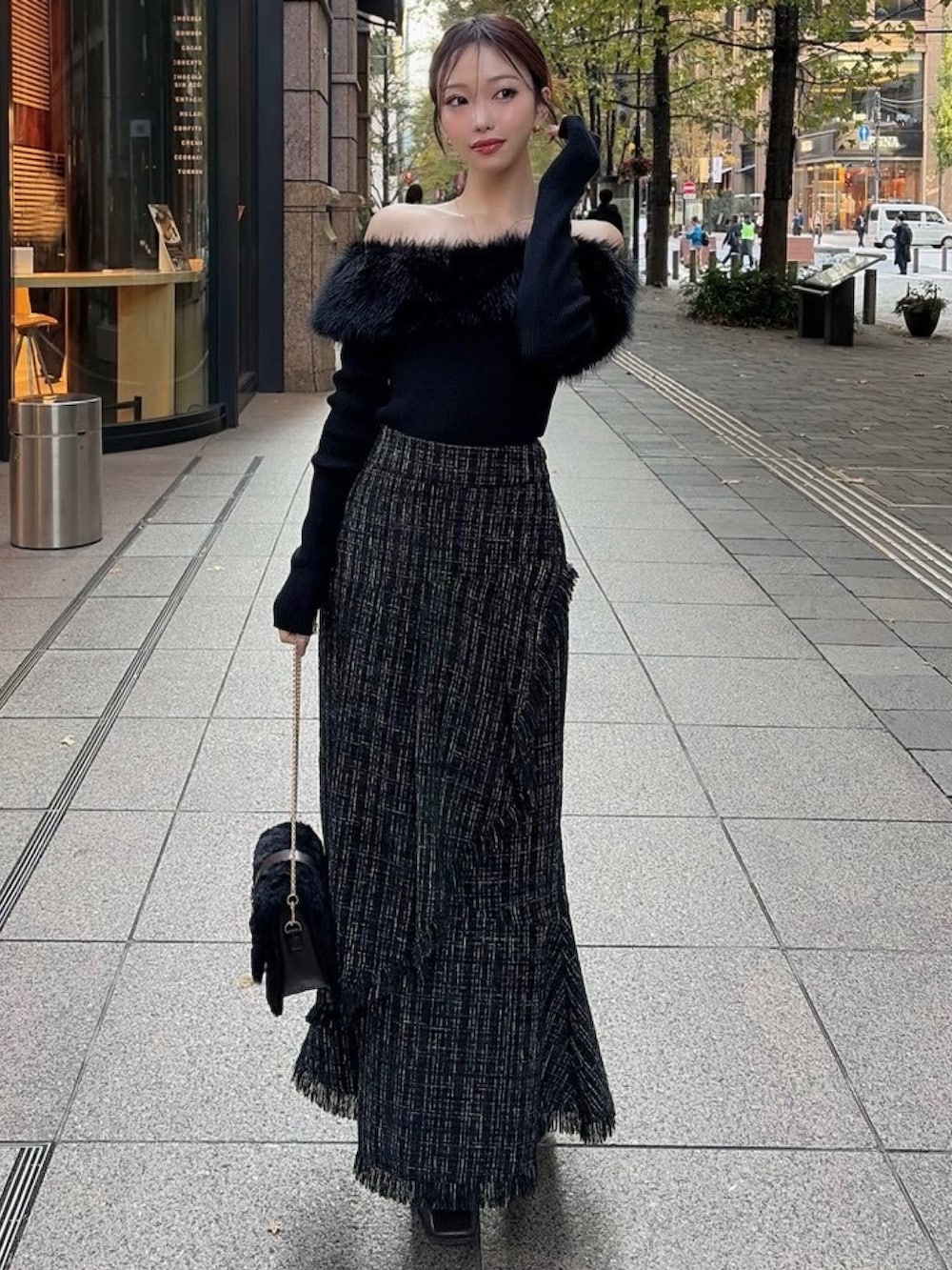 ブラック系のニット/セーター、ブラック系のスカート、ブラック系のハンドバッグを着用したレディースの冬コーディネートの2枚目の写真