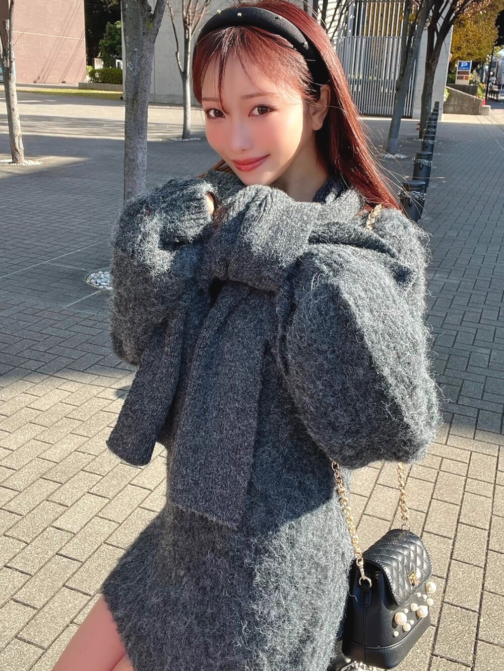 グレー系のワンピース、ブラック系のショルダーバッグを着用したレディースの冬コーディネートの2枚目の写真