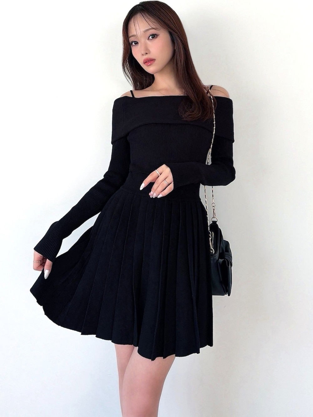 ブラック系のワンピース、ブラック系のハンドバッグを着用したレディースの春コーディネートの2枚目の写真