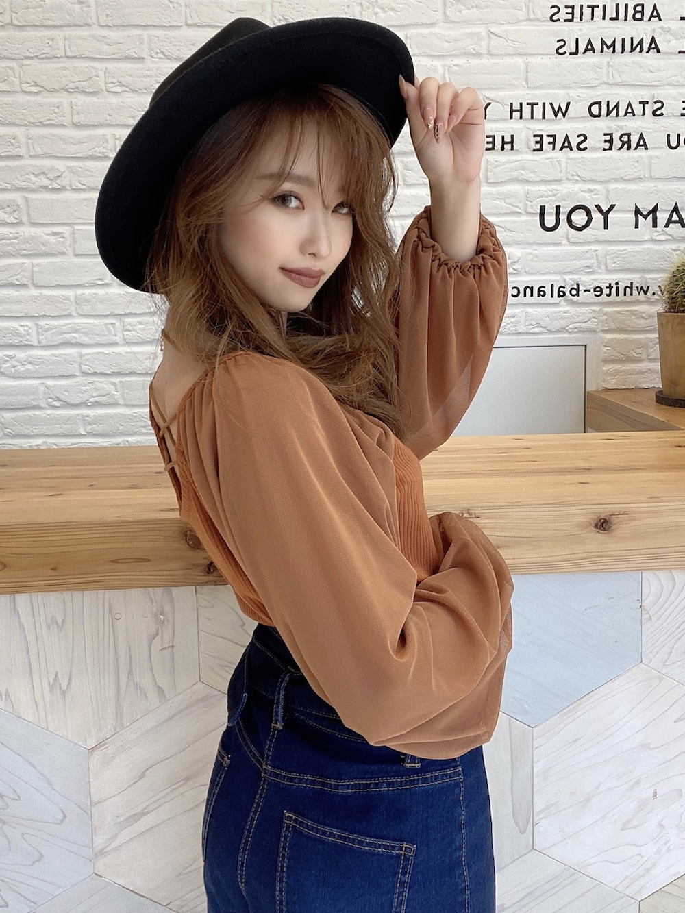 ブルー系のデニムパンツ、ブラウン系のTシャツ/カットソー、ブラック系のハットを着用したレディースの夏コーディネートの2枚目の写真