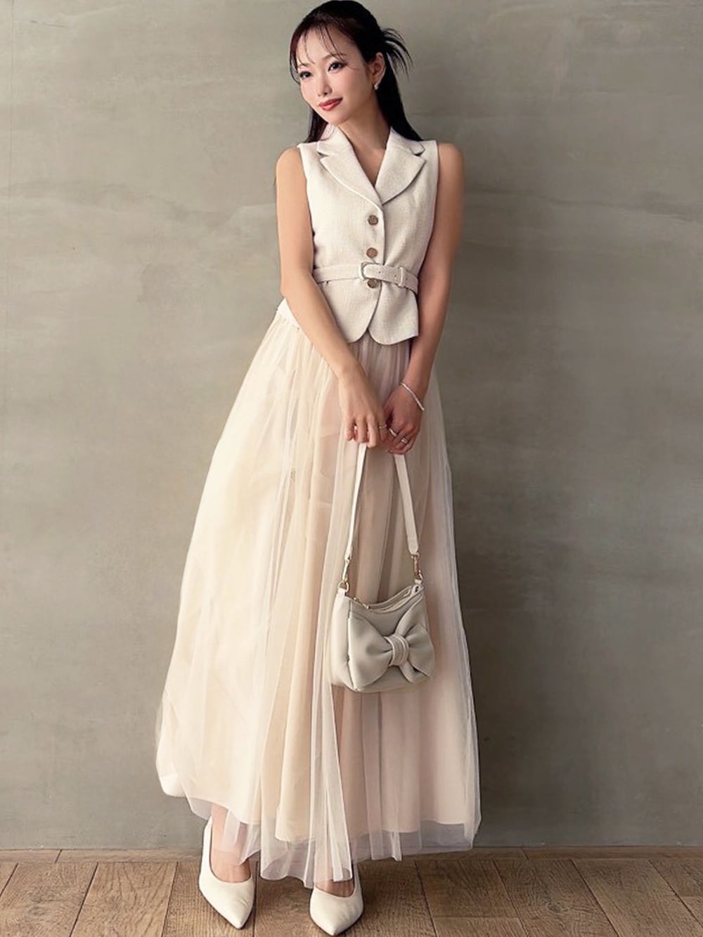 ホワイト系のワンピース、ホワイト系のパンプス、ホワイト系のハンドバッグを着用したレディースの春コーディネートの3枚目の写真