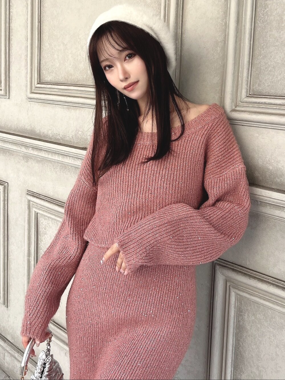 ピンク系のニット/セーター、ピンク系のスカート、シルバー系のハンドバッグを着用したレディースの秋コーディネートの2枚目の写真