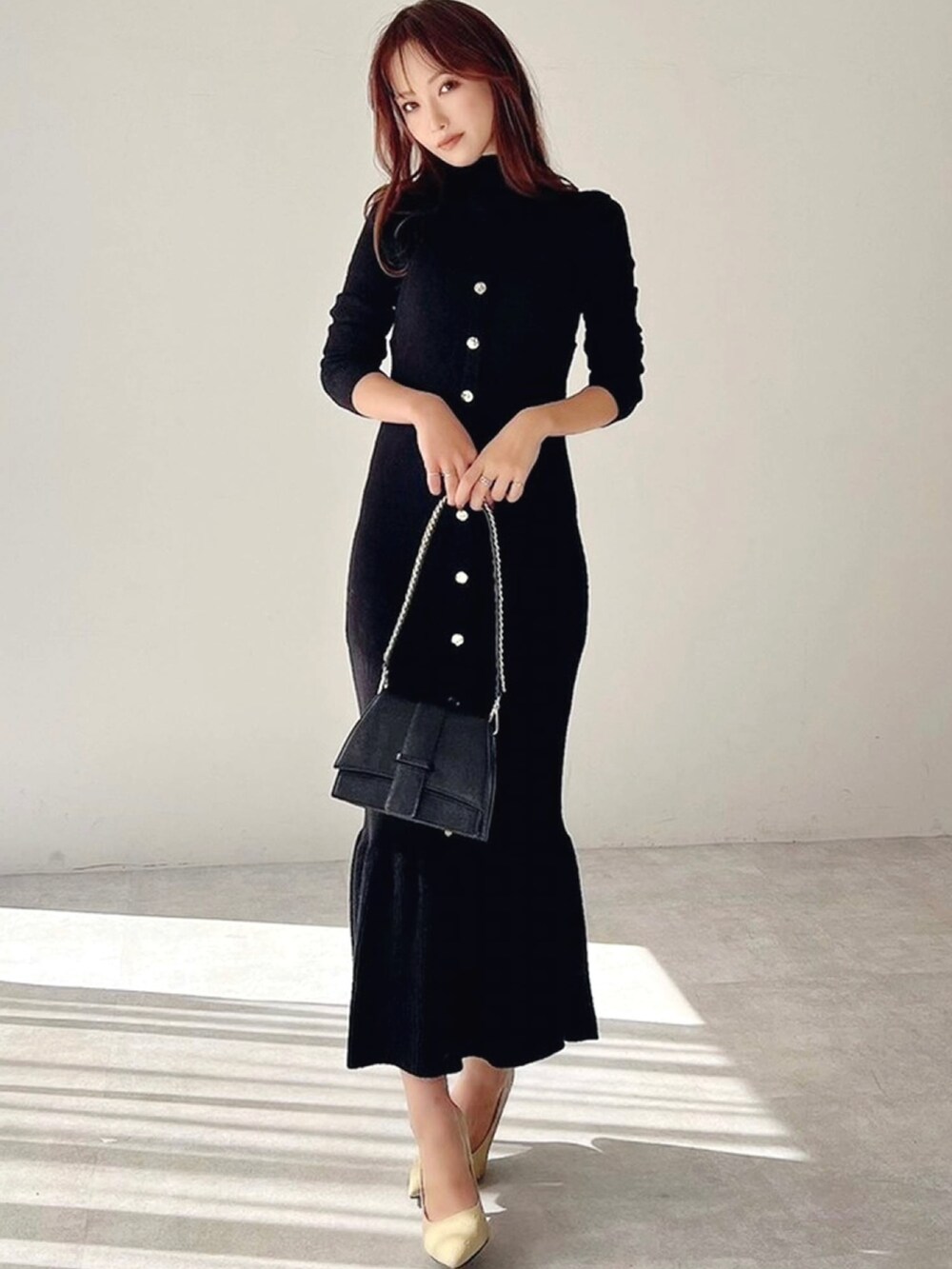 イエロー系のパンプス、ブラック系のワンピース、ブラック系のハンドバッグを着用したレディースの冬コーディネートの3枚目の写真