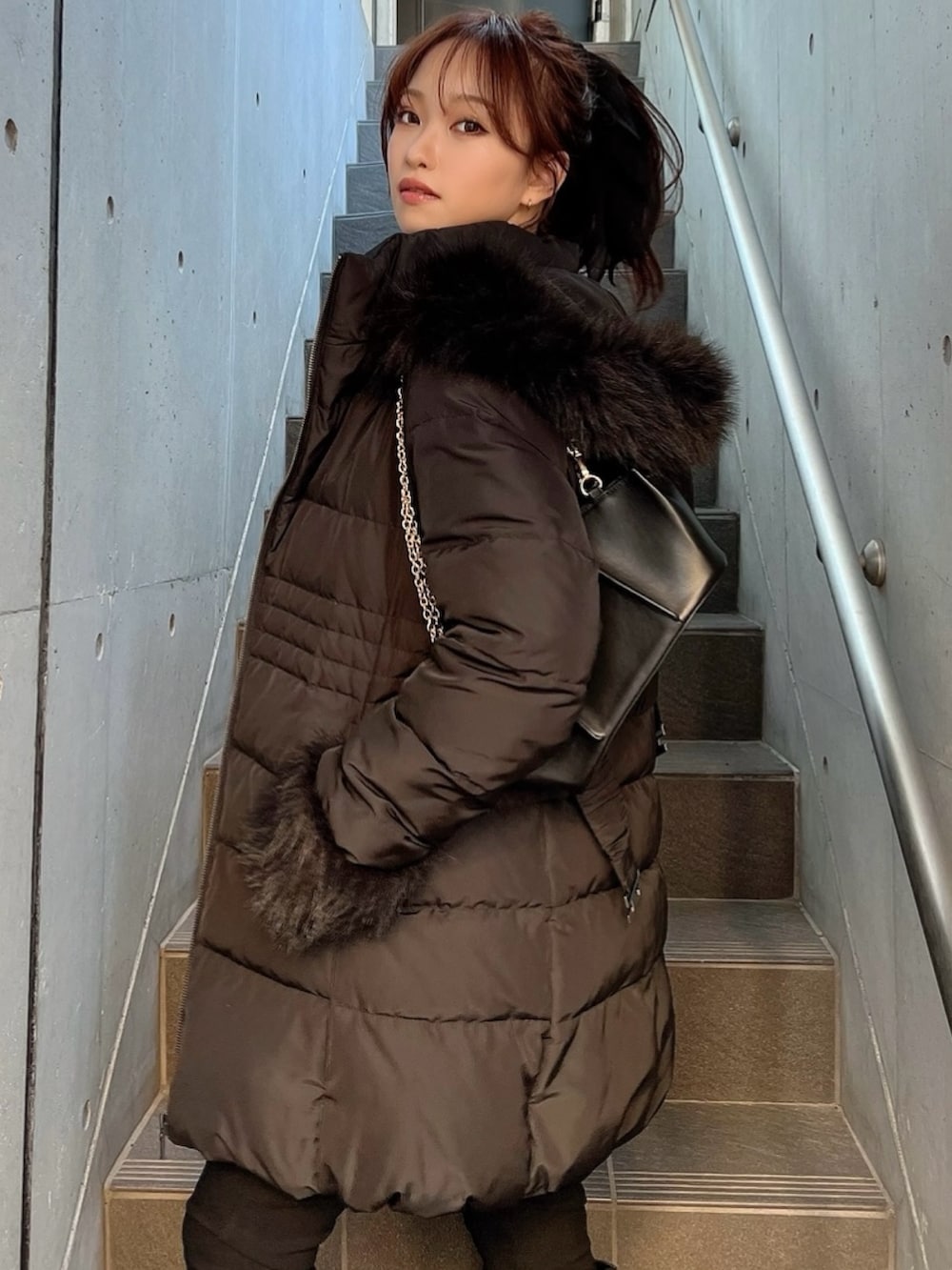 ブラック系のダウンジャケット/コート、グレー系のニット/セーター、ブラック系のブーツを着用したレディースの秋コーディネートの2枚目の写真