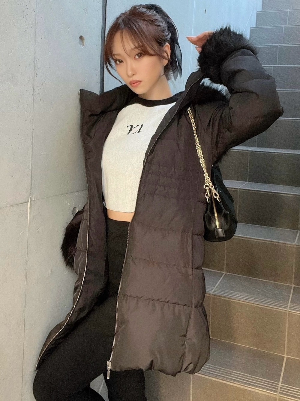 ブラック系のダウンジャケット/コート、グレー系のニット/セーター、ブラック系のブーツを着用したレディースの秋コーディネートの4枚目の写真