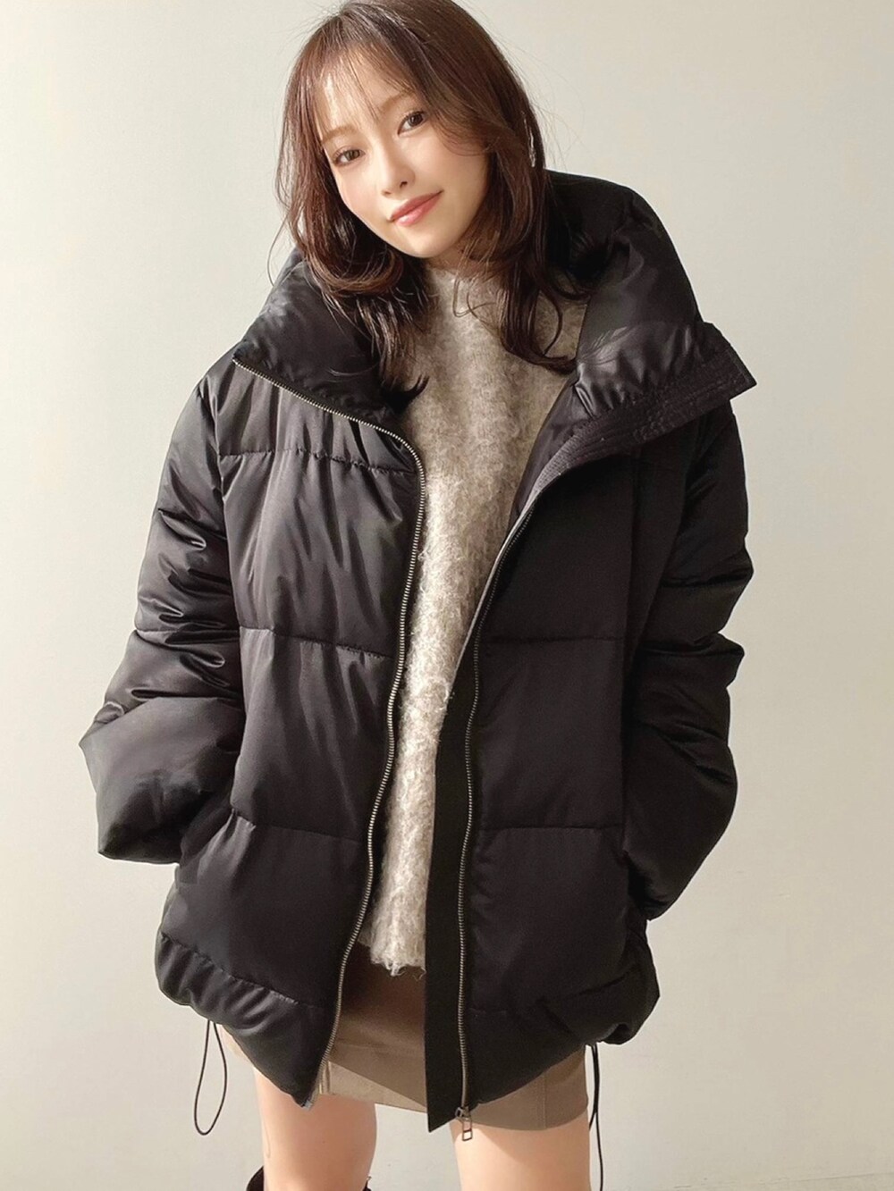 ブラック系のダウンジャケット/コート、ブラック系のブーツ、ベージュ系のニット/セーターを着用したレディースの冬コーディネートの2枚目の写真