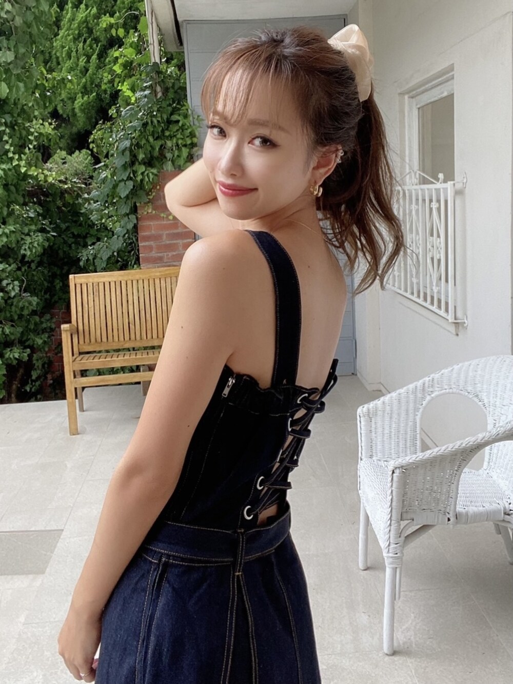 ブラック系のパンプス、ブルー系のジャンパースカート、ピンク系のシュシュを着用したレディースの夏コーディネートの5枚目の写真